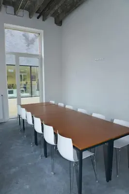a long wooden table with white chairs around it at Jeugdverblijfcentrum Schotte in Aalst