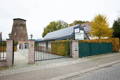 a fence in front of a house with a silo at Het Molenhuisje in Brecht