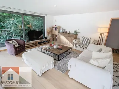 a living room with white furniture and a large window at Appartement 120m2 plus terrasse in Brussels