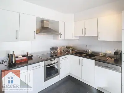 a white kitchen with white cabinets and appliances at Appartement 120m2 plus terrasse in Brussels