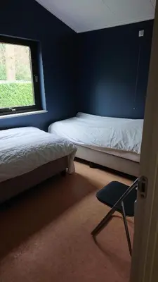 a room with two beds and a chair and a window at Tregadata guesthouse in Overijse