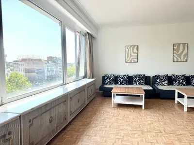 a living room with a couch and a large window at Amerika Apartments in Antwerp