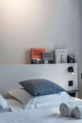 a white bedroom with a bed with books above it at Studio for 2 in City of Ghent in Ghent