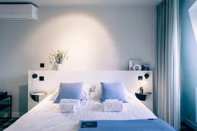 a bedroom with a large white bed with blue accents at Cozy Studio for Two in Central Ghent in Ghent