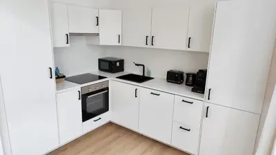 a white kitchen with white cabinets and appliances at Le Cocon Studio in Brussels