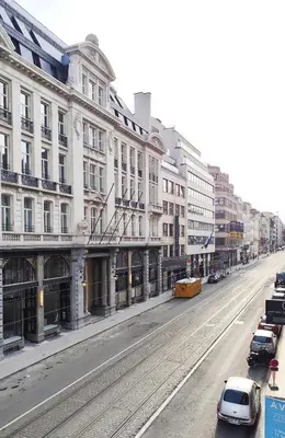 an empty city street with buildings and a white car at Le Cocon Studio in Brussels