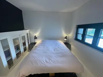 a large white bed in a bedroom with two windows at Appartement à proximité de Bruxelles in Meise