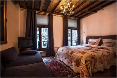 a bedroom with a bed and a couch and windows at Living History - Drie Koningen in Antwerp