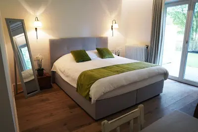 a bedroom with a large bed and a mirror at Boutique hotel-restaurant De Lindehoeve in Tessenderlo