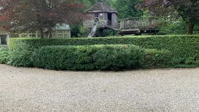 a large green hedge in front of a park at Boutique hotel-restaurant De Lindehoeve in Tessenderlo