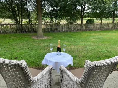 a bottle of wine sitting on a table with two chairs at Boutique hotel-restaurant De Lindehoeve in Tessenderlo