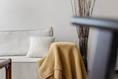 a white chair with a blanket on it next to a vase at Mubi-Stay - Appartement chalereux au centre ville D'Anvers in Antwerp