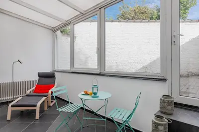 a room with chairs and a table and windows at Brussels Benit Ixelles House in Brussels