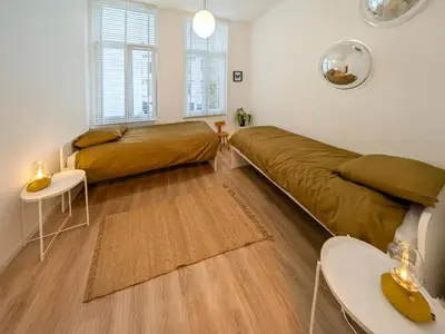 a living room with two beds and a table at Guesthouse Josephine - Antwerpen in Antwerp