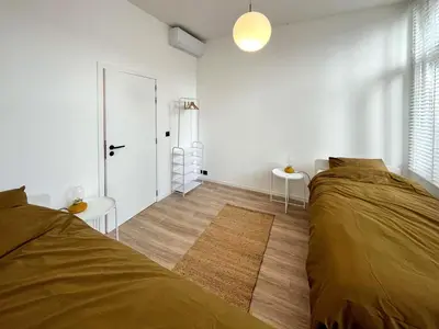 a white bedroom with two beds and a door at Guesthouse Josephine - Antwerpen in Antwerp