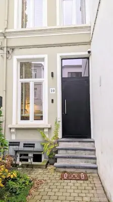 a white house with a black door and stairs at Guesthouse Josephine - Antwerpen in Antwerp