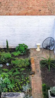 a garden with a vase sitting next to a brick wall at Guesthouse Josephine - Antwerpen in Antwerp
