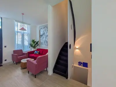 a living room with a red couch and a staircase at Guesthouse Josephine - Antwerpen in Antwerp