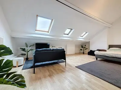 a bedroom with a bed and a couch in a room with skylights at Porte de Namur in Brussels