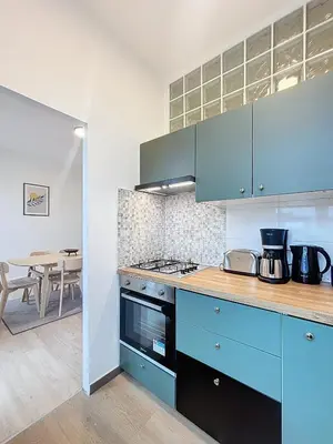 a kitchen with blue cabinets and a table in the background at Porte de Namur in Brussels