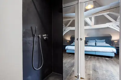 a bathroom with a shower and a bed in a bedroom at Ganda Rooms & Suites in Ghent