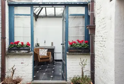 an open door to a patio with red flowers at Ganda Rooms & Suites in Ghent