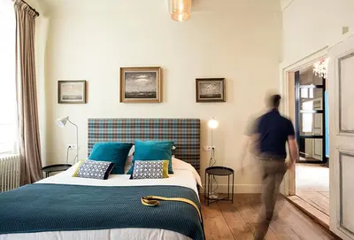 a man walking past a bed in a room at Ganda Rooms & Suites in Ghent