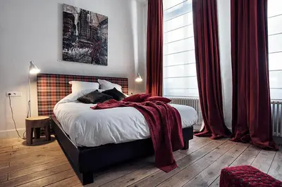 a bedroom with a bed with a red blanket on it at Ganda Rooms & Suites in Ghent