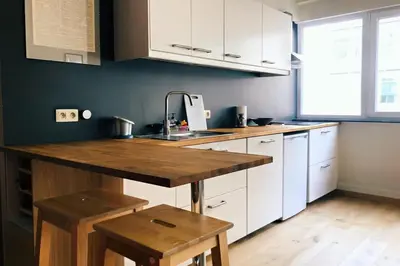 a kitchen with white cabinets and a wooden counter top at Renovated one bedroom apartment Schuman area in Brussels
