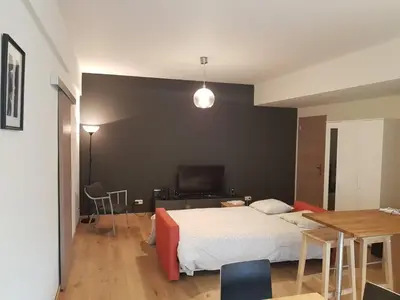 a bedroom with a bed and a table and a television at Renovated one bedroom apartment Schuman area in Brussels