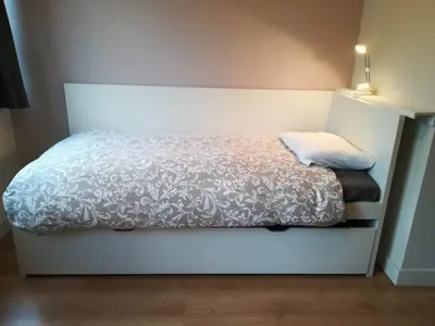 a bedroom with a bed with a white comforter at Charming little studio in Brussels