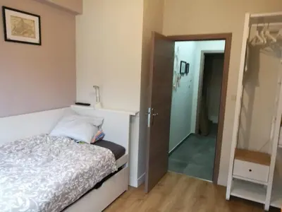 a bedroom with a white bed and a mirror at Charming little studio in Brussels