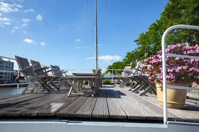 a wooden deck with a table and chairs and flowers at Hotel The Boatel in Ghent