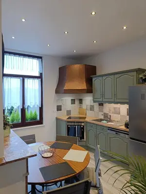a kitchen with green cabinets and a wooden table at Modern Triplex 140m2 - 4 bedrooms, 1 living room & 2 bathrooms - 8 people in Brussels city in Brussels