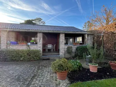 a small brick house with a patio with plants at Vakantiehuis De Bosrand Goor-Asbroek in Hulshout