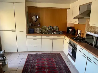 a kitchen with white cabinets and a rug on the floor at Vakantiehuis De Bosrand Goor-Asbroek in Hulshout