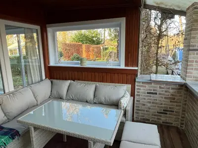 a living room with a couch and a table at Vakantiehuis De Bosrand Goor-Asbroek in Hulshout