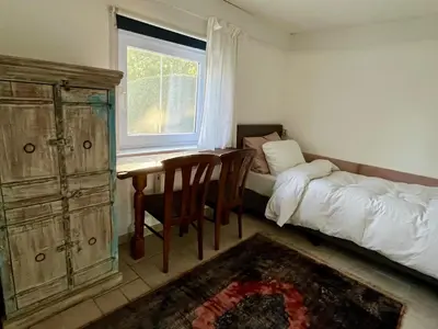 a bedroom with a bed and a desk and a window at Vakantiehuis De Bosrand Goor-Asbroek in Hulshout