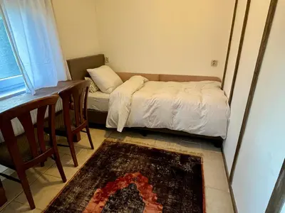 a small bedroom with a bed and a desk and a table at Vakantiehuis De Bosrand Goor-Asbroek in Hulshout