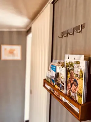a shelf with books and pictures on it at CASA LAGO gezellige chalet aan het water in Geel