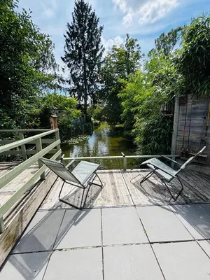 two chairs sitting on a patio next to a river at CASA LAGO gezellige chalet aan het water in Geel