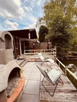 a patio with two chairs and a house at CASA LAGO gezellige chalet aan het water in Geel