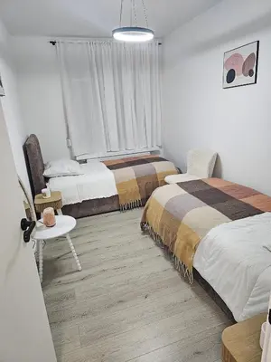 a bedroom with two beds and a table and a window at Modern Comfort Spot Apartments in Antwerp