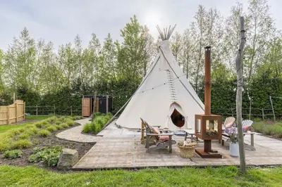 a white teepee tent with a table and chairs at Tipi Marie met hotutub in de tuin in Kaprijke