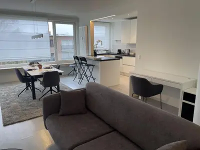 a living room with a couch and a table and a kitchen at Chez HN Confort et Style in Edegem