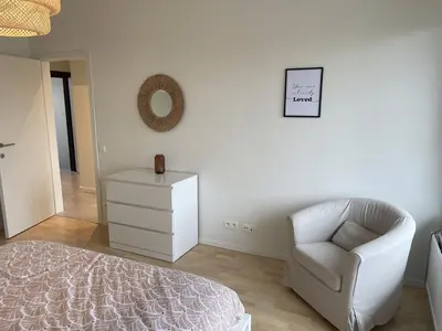 a white bedroom with a chair and a mirror at Chez HN Confort et Style in Edegem