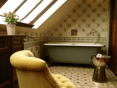 an attic bathroom with a tub and a chair at Maison Flagey Brussels in Brussels
