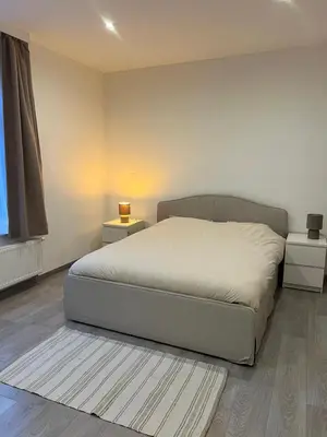 a bedroom with a bed and two night stands at Appartement confortable avec garage premier étage sans terrasse in Brussels