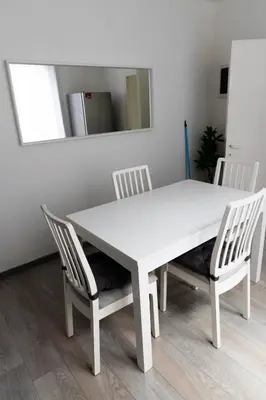 a white dining room table with two chairs and a mirror at Appartement confortable avec garage premier étage sans terrasse in Brussels