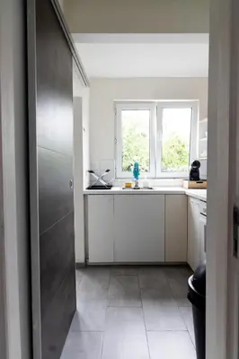a kitchen with white cabinets and a window at Appartement confortable avec garage premier étage sans terrasse in Brussels